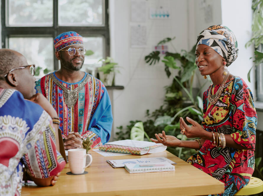 Happy African American woman gesticulating while chatting with her male colleague during coffee brake in office